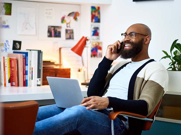 Man in his 30s sitting on chair with laptop, on phone call, communication, owner, entrepreneur